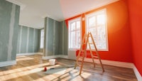an empty room with red walls and a ladder