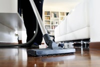 a person vacuuming a hardwood floor in a living room